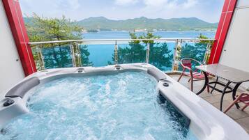 A hot tub with a view of a body of water and mountains.