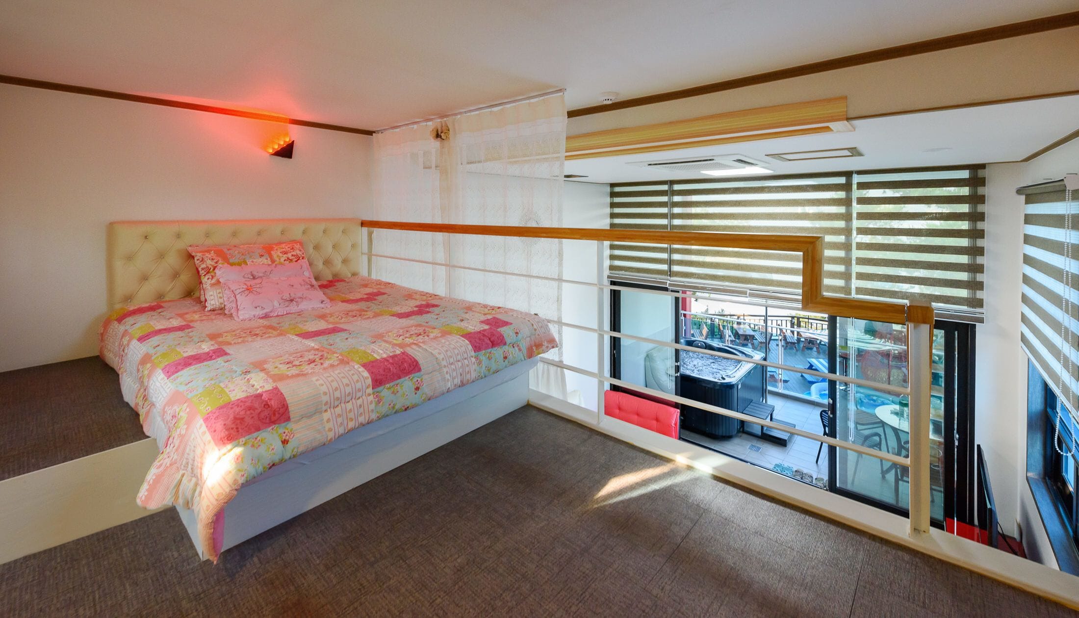 Un dormitorio con cama, ventana con persianas y vistas a un área exterior.