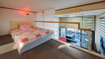 Un dormitorio con cama, ventana con persianas y vistas a un área exterior.