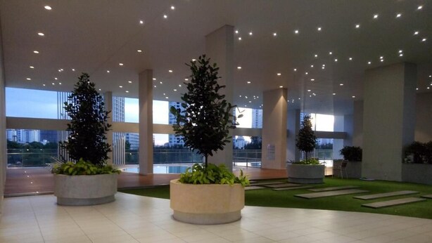 A spacious lobby with large windows, potted plants, and a tiled floor.