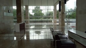 A spacious lobby with a wet floor, glass walls, and a bench area.