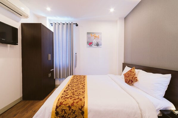 Een hotelkamer met een bed, een televisie, een kast en een schilderij aan de muur.