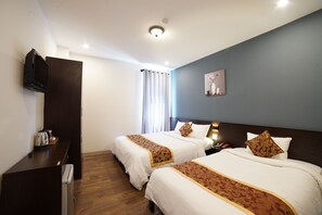Hotelkamer met twee bedden, een flatscreen televisie, een bureau met waterkoker en een nachtkastje met lamp.