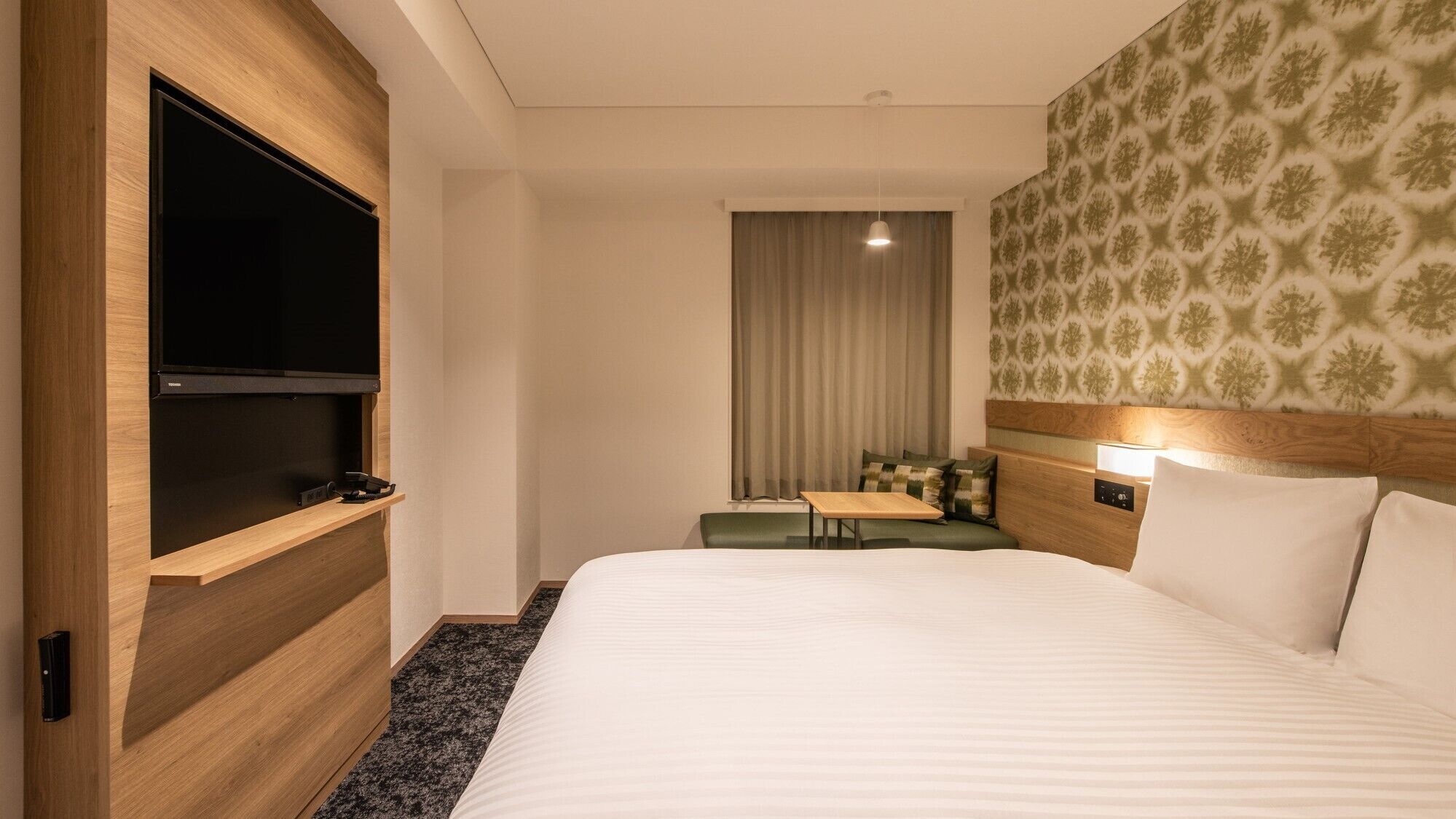 Une chambre d’hôtel avec un grand lit, un téléviseur à écran plat, une petite table et un coin salon.