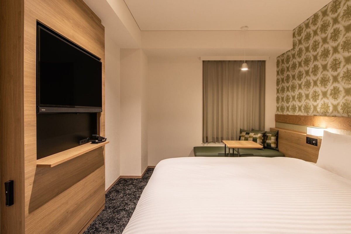 Ein Hotelzimmer mit einem großen Bett, einem Flachbildfernseher, einem kleinen Tisch und einer Sitzecke.