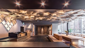 Un intérieur moderne avec un comptoir d’accueil central, un long comptoir et un espace salon doté d’une grande fenêtre offrant une vue sur la ville.