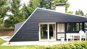 A modern house with a black exterior, a glass door entrance, and a patio with outdoor furniture. - Haus 11 by Interhome (Gerolstein)