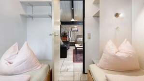 A modern hotel room with a minimalist design, featuring two beds with matching pillows, a small kitchenette, and a view through an open door to a dining area. - Haus 11 by Interhome (Gerolstein)