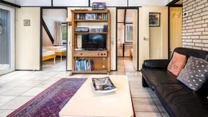A living room with a black leather sofa, a wooden bookshelf, and a television. - Haus 11 by Interhome (Gerolstein)