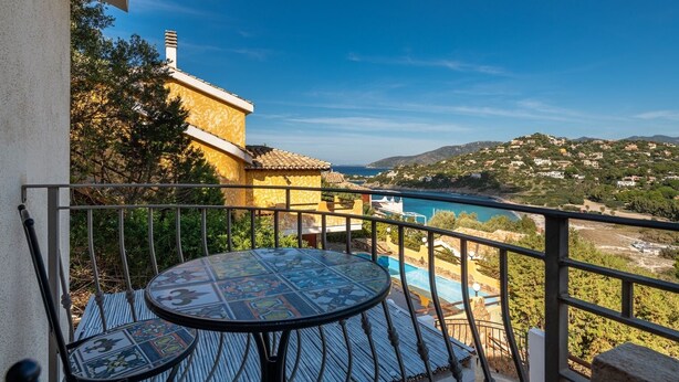 A balcony with a view of a coastal landscape, a pool, and a tiled table. - Villa Camelia panoramic villa facing the sea (Torre Delle Stelle (Maracalagonis))