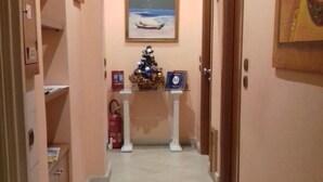 Un pasillo con un árbol de Navidad, un cuadro en la pared y una puerta al final.