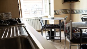 Una cocina con estufa a gas, pileta y comedor con mesa y sillas.