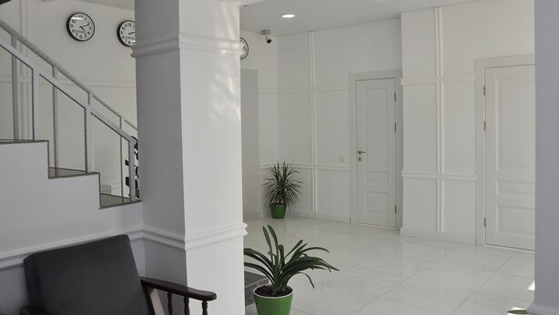 Un hall d’entrée spacieux avec un escalier, des murs blancs et une plante en pot.