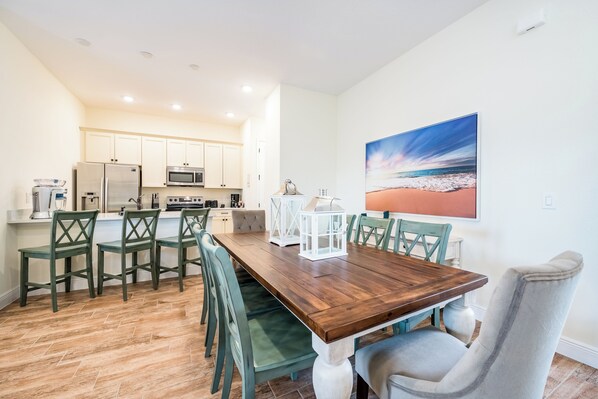 Una cocina moderna con armarios blancos, electrodomésticos de acero inoxidable y una mesa de comedor de madera con sillas.