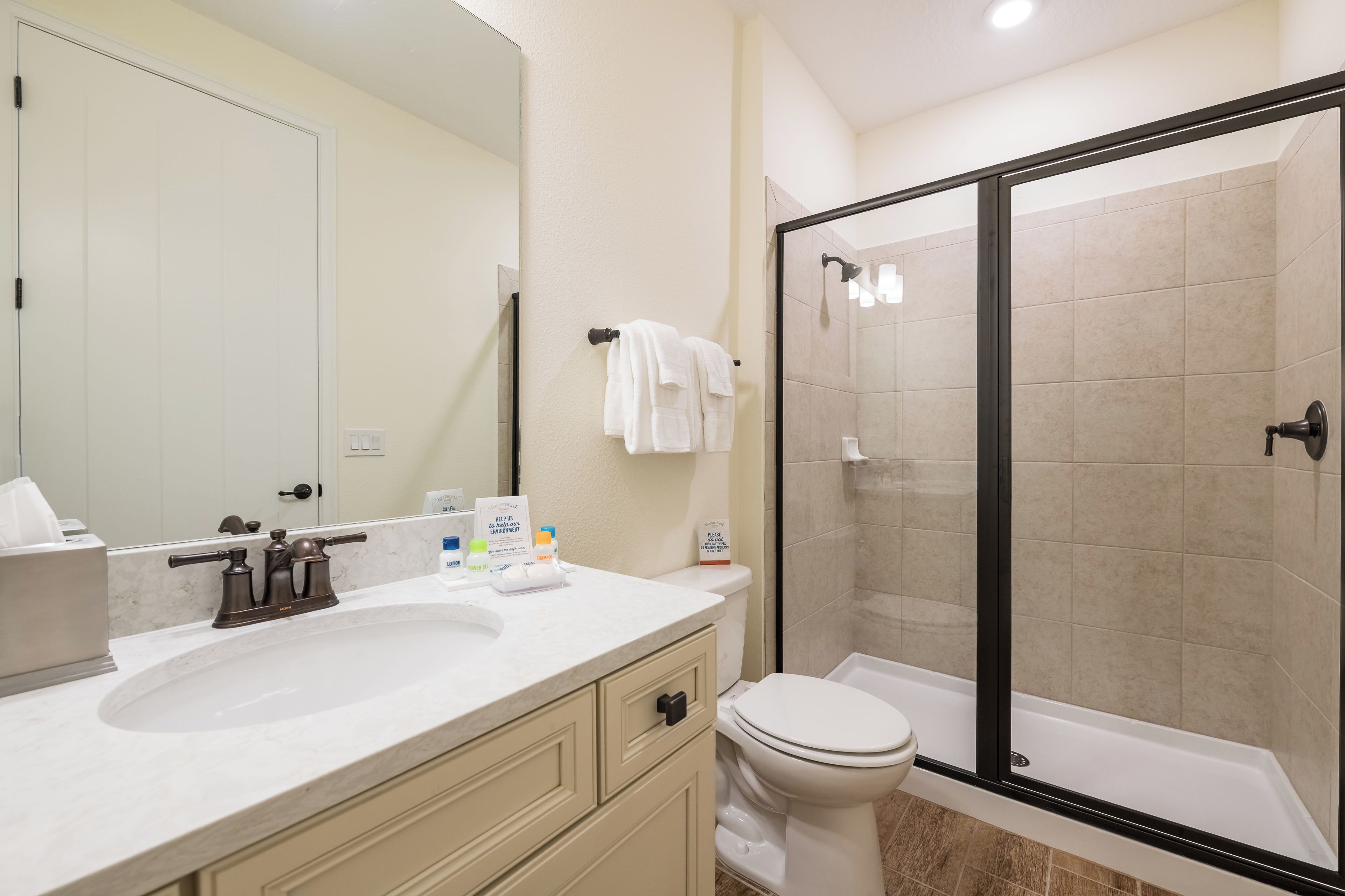 Un baño moderno con lavamanos, inodoro y ducha con mampara de vidrio.