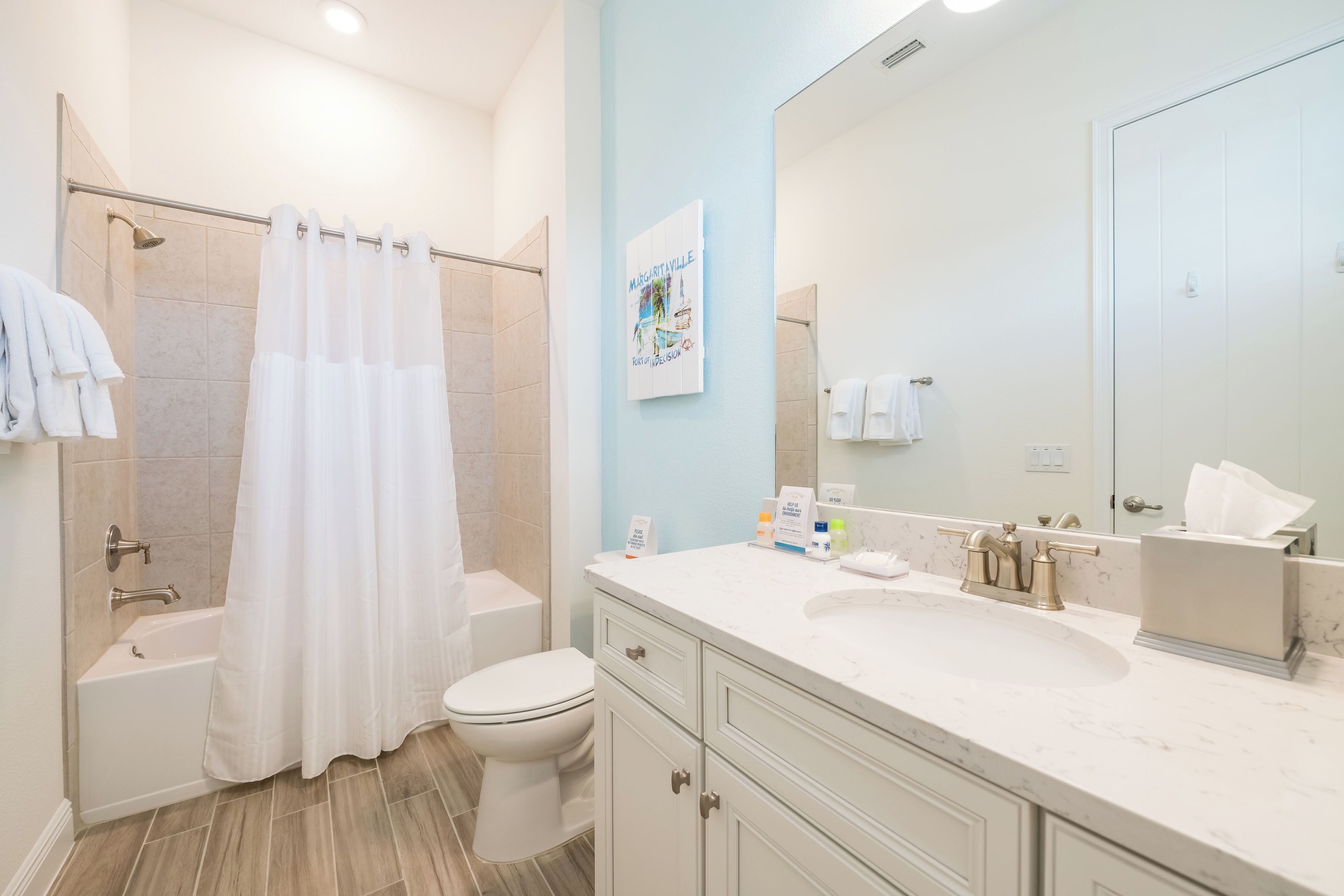 Un baño con bañera, inodoro y un espejo grande.