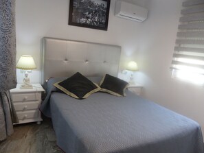 A bedroom with a bed, two bedside lamps, a wall-mounted air conditioner, and a framed picture above the bed. - Villa private pool sea view 5 min walk, air conditioning, handicapped access 1 to 7P+2optional  (San Juan de los Terreros)