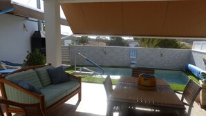An outdoor patio with a pool, a wooden table, and wicker furniture. - Villa private pool sea view 5 min walk, air conditioning, handicapped access 1 to 7P+2optional  (San Juan de los Terreros)