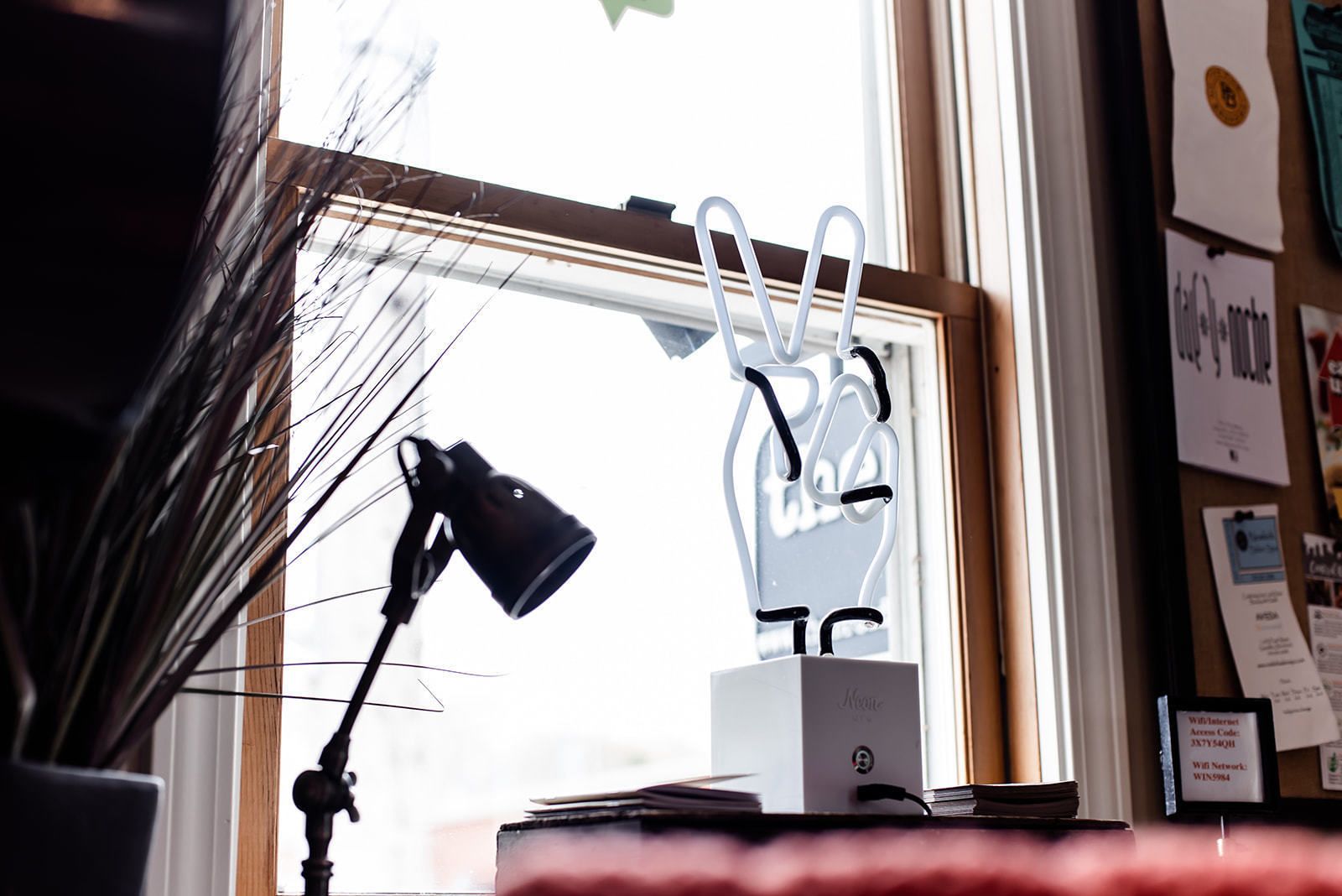 A desk with a lamp, a white box, and a window with a view of the outside.