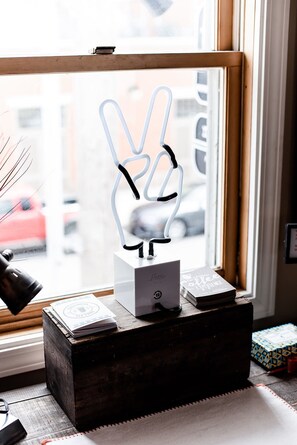 A desk with a white object resembling a peace sign, a lamp, and a stack of books. - The Loft (Granville)
