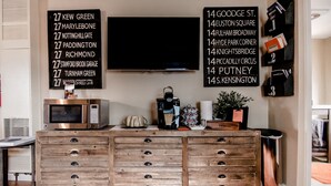 A kitchen with a wooden cabinet, a microwave, a coffee maker, and a TV mounted on the wall.