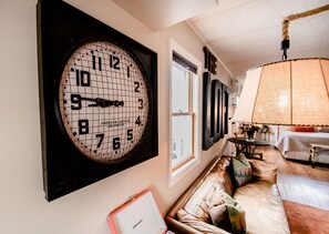 A living room with a large wall clock, a sofa, and a hanging lamp. - The Loft (Granville)