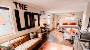 A cozy loft-style bedroom with a large bed, a sofa, and a desk area.