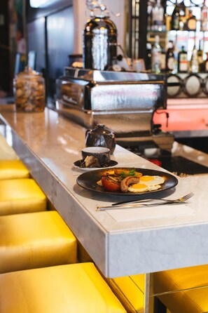 Un espace bar avec un comptoir, des tabourets et une assiette de nourriture.