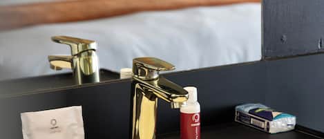 A bathroom with a sink, mirror, and toiletries.