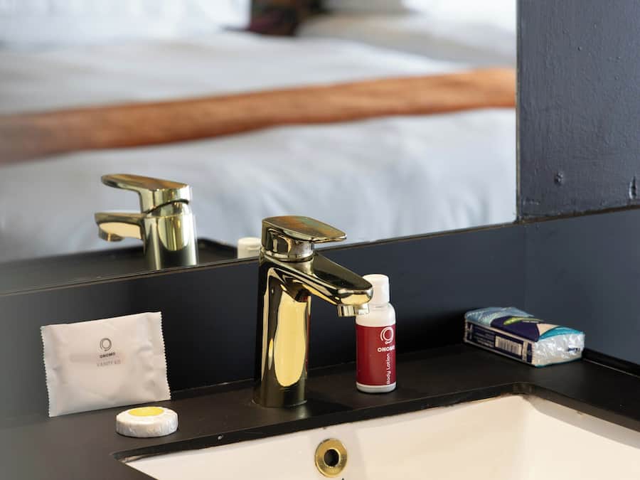 A bathroom with a sink, mirror, and toiletries.