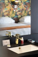 A bathroom with a sink, mirror, and toiletries.