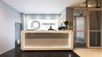 Ein Empfangsschalter mit einem Schild mit dem Aufdruck 'ONOMO' und einem modernen Innenraumdesign.