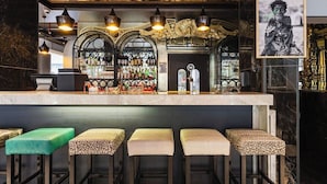 A bar area with a marble countertop, multiple stools, and a variety of bottles and glasses.