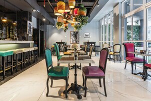 A restaurant with a bar area, multiple dining tables, and chairs.