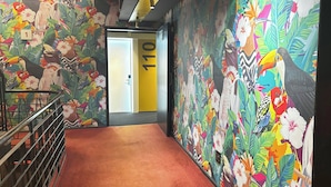 A hallway with vibrant tropical murals, a red carpet, and a door marked with the number 110.