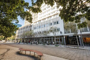 En modern byggnad med flera våningar, stora fönster och en butikslokal på markplan.