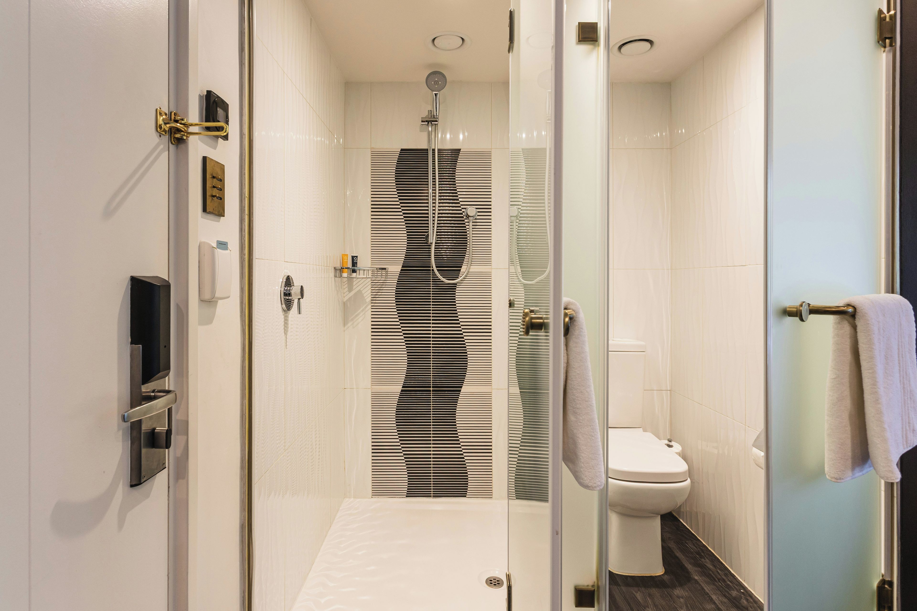 Un baño moderno con cabina de ducha de vidrio, un inodoro y un perchero para toallas.