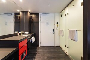 A modern bathroom with a large mirror, a black countertop, and a red cabinet.