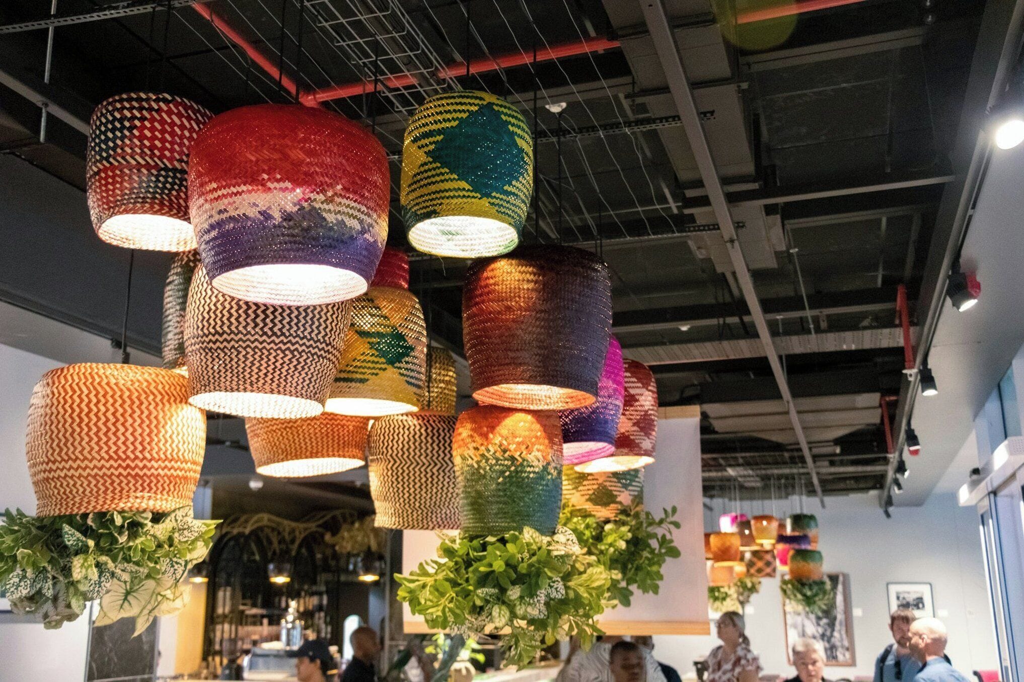 A ceiling with multiple hanging lamps and potted plants.