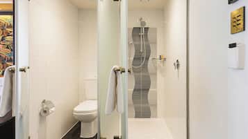 Een moderne badkamer met een douchecabine van glas, een toilet en een handdoekhouder.