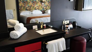 Une salle de bain moderne avec un grand miroir, un lavabo, un meuble rouge et un pouf rouge.