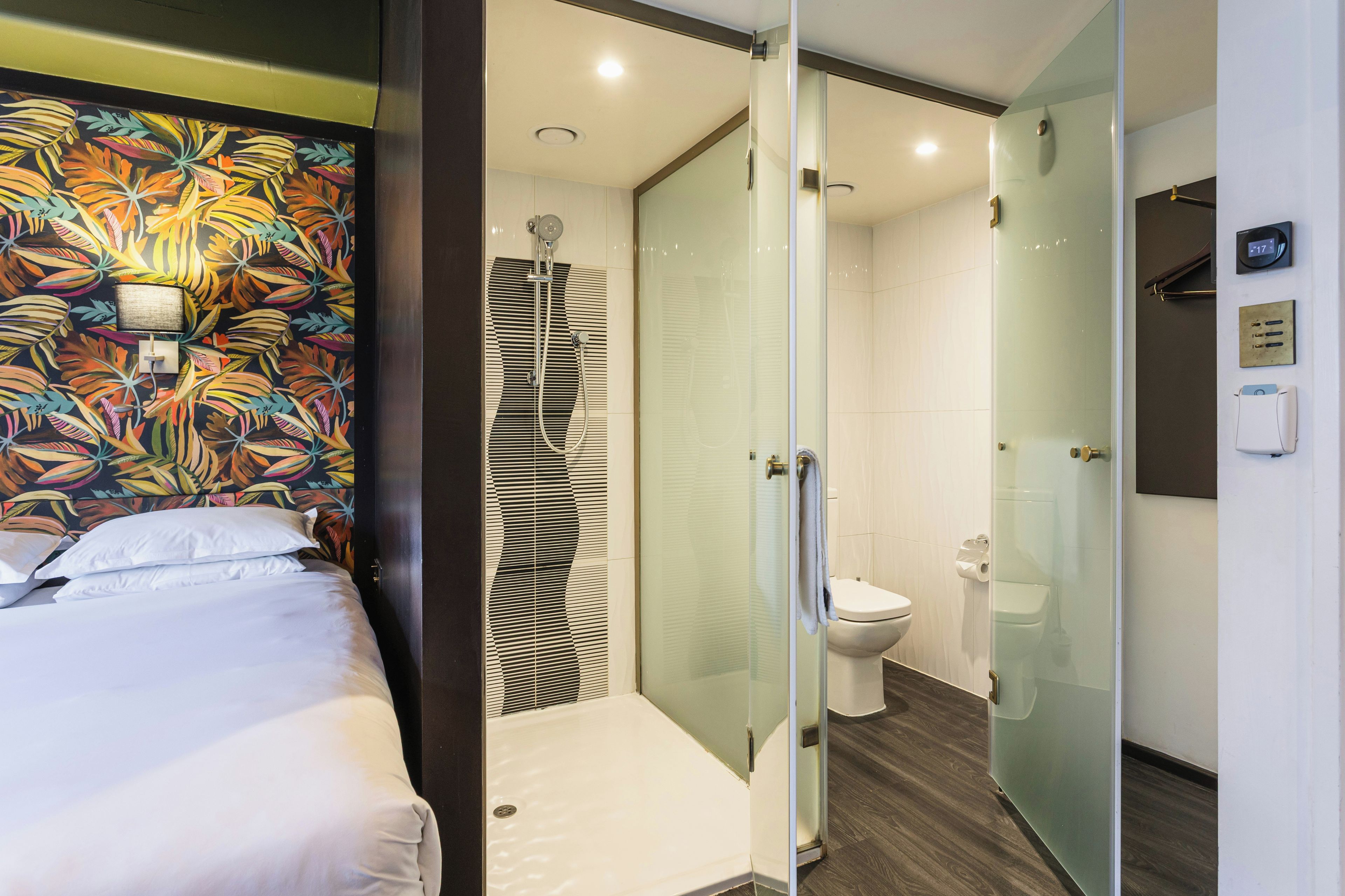 A hotel room with a bed, a shower, and a toilet.