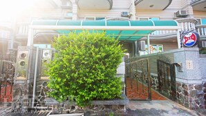 A hotel entrance with a green awning, stone walls, and a sign indicating a Golden Year.