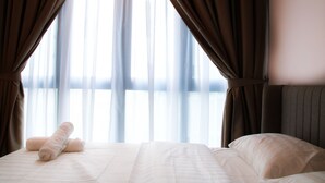 A hotel room with a bed, curtains, and a view through the window. - H2O Residences by Victoria Home (Petaling Jaya)