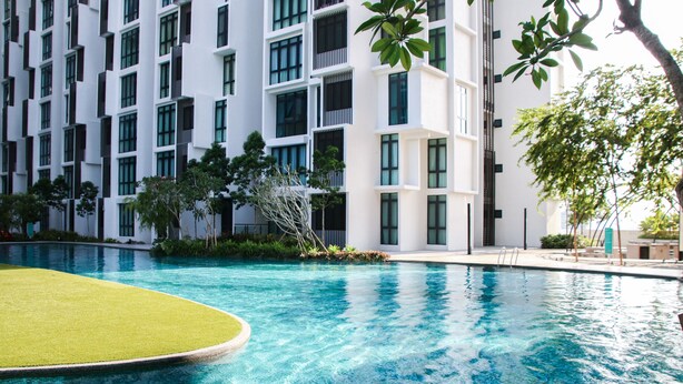 A swimming pool with a green deck, surrounded by a modern building with multiple balconies and windows. - H2O Residences by Victoria Home (Petaling Jaya)
