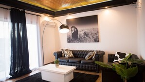 A modern living room with a black leather sofa, a white coffee table, and a large black and white photograph on the wall.
