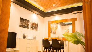 A modern dining area with a wooden ceiling, white walls, and black chairs.