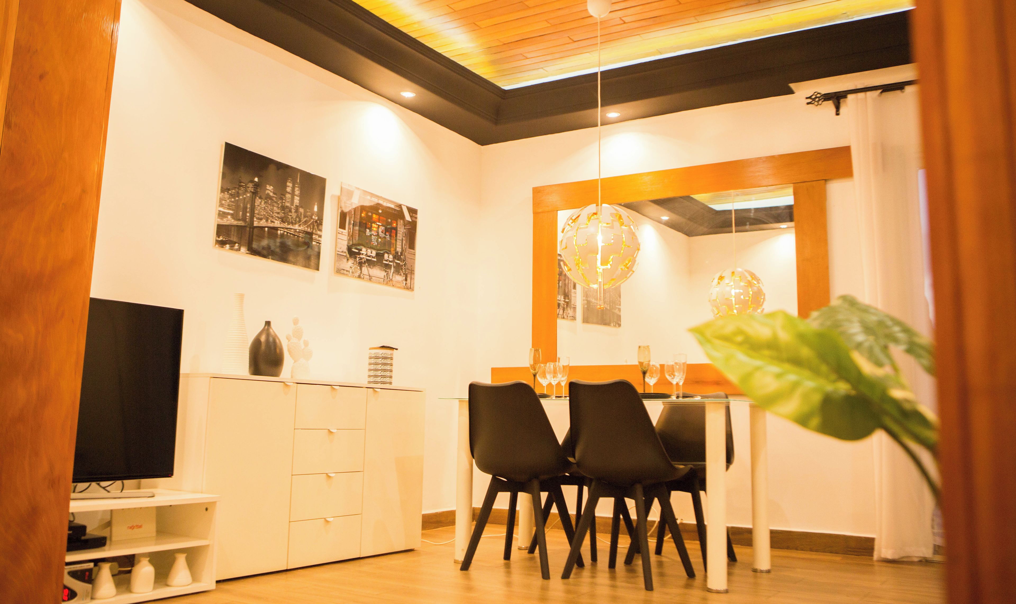 Un comedor moderno con techo de madera, paredes blancas y sillas negras.
