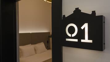 Ett hotellrum med en säng, en sänggavel och en skylt som visar att det är rum nummer 01.