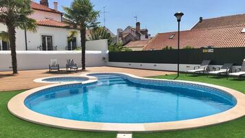 Una piscina al aire libre de temporada, sombrillas